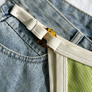Nahaufnahme von cremefarbenen Bikini-Trägern mit Schildpatt-Ringen und Metallschnallen