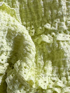 Close-up of light green crochet lace fabric texture with intricate knit patterns