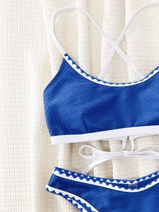 Flat lay of blue waffle texture bikini with white strappy back details on knit background