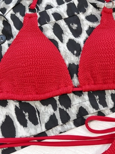 Close-up of red ruched bikini top with silver metal ring and textured stretch fabric