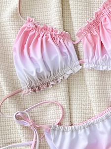 Bikini degradado rosa y blanco con bordes de volantes y braguita con lazos sobre tela gofrada