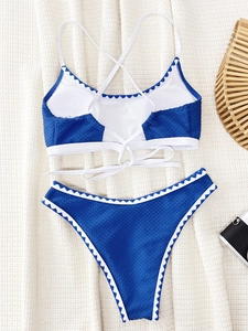 Close-up of blue scalloped bikini set with textured fabric and white trim on fabric background