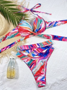Flat lay of colorful marble print bikini set with high-waisted crossover bottoms on a beach towel