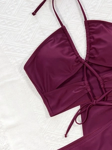 Close-up of wine red halter bikini top with criss-cross straps and pleated details