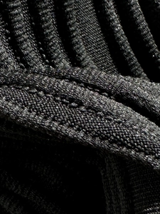 Detailed macro of black ribbed bikini fabric with subtle sparkle and precision stitching