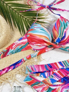Flat lay of marble print bikini with halter top and side-tie bottom on beach props