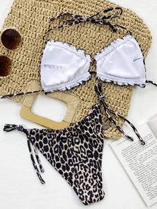 Detailed flat lay of leopard print bikini set with material labels and beach accessories