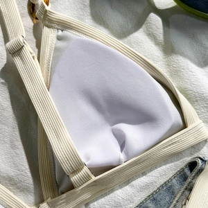 Detailansicht eines beigen Bikini-Oberteils mit Schildpatt-Ring und Metallschiebern
