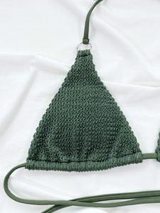 Detail of dark green smocked bikini top featuring silver metal ring and ribbed texture
