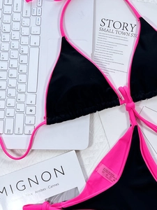 Detail of neon pink and black bikini showing premium 80% nylon fabric and contrast stitching