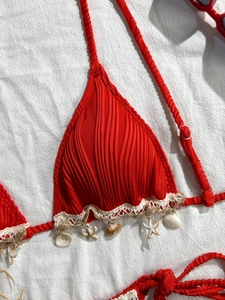 Detailed view of red ribbed bikini top with bohemian shell and starfish charms