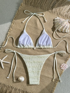 White smocked triangle bikini set with shell charms on a woven beach mat background