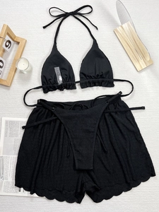 Detailliertes Flatlay eines schwarzen dreiteiligen Bikinisets mit gesmokter Textur