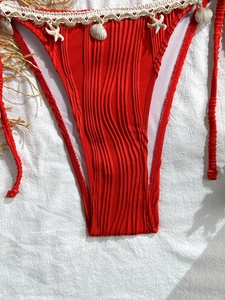 Close-up of red ribbed bikini bottoms with crochet lace, seashells, and starfish detail