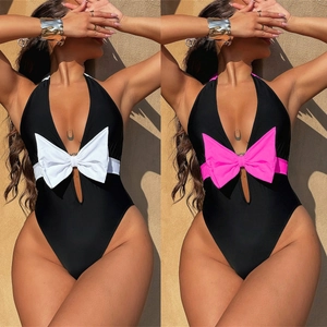 Detail of cutout one-piece swimsuit featuring a large contrast bow in white and pink colors