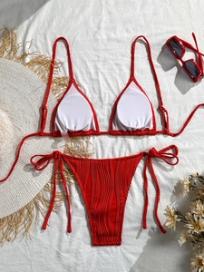 Detailed flat lay of red ribbed bikini set with tie-side bottoms and summer accessories