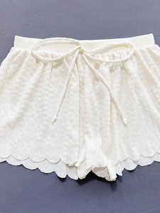 Detail von cremefarbenen Bikini-Shorts mit Kordelzug am Bund und gewelltem Saumdesign