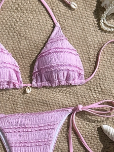 Detailed view of light purple smocked bikini top with halter neck and shell accents