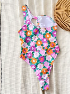 Floral one-piece swimsuit with one-shoulder cutout and tie detail on beige texture