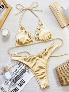Détail à plat d'un bikini doré métallisé avec anneaux et accessoires décoratifs