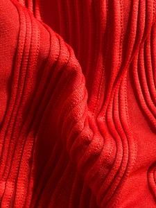 Macro shot of red textured bikini fabric featuring 3D wavy ribbed knit patterns