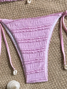 Detail of light purple smocked bikini bottom with side ties and seashell charms