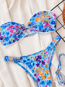 Light blue floral bikini set with U-shaped gold ring and wave trim in a flat lay view