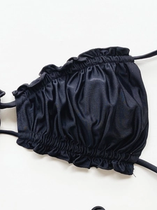 Detailed macro view of black bikini top with ruffled edges and drawstring design