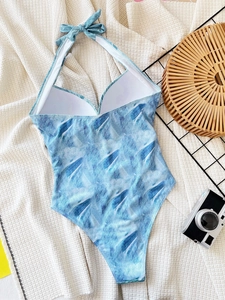 Detailed flat lay of blue tie-dye halter swimsuit with chest pads and resort accessories