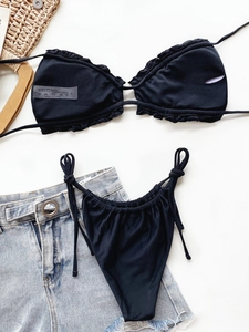 Flat lay of black halter bikini set with straw hat and denim shorts for summer vibe