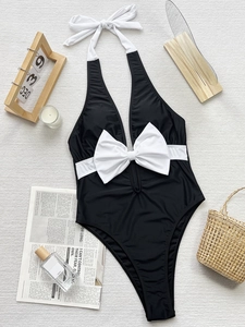 Detail of a black and white one-piece swimsuit with a large bow and halter neck style