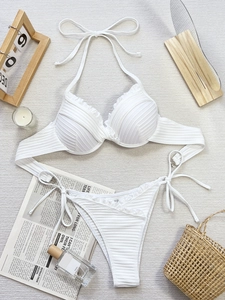 Detailed view of white ribbed bikini set with ruffle edges on a flat lay background