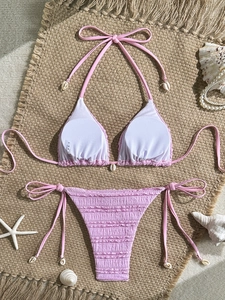 Detailed view of pink textured bikini with seashell accents on a beach straw mat