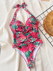 Detail of tropical leaf print one-piece swimsuit with halter neck and ruching detail