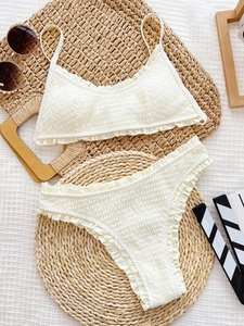 White ruffle bikini set with smocked texture flat lay on summer vacation background