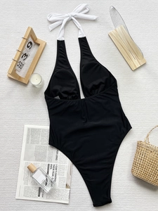 Flat lay of a black and white one-piece swimsuit with halter ties and size S label