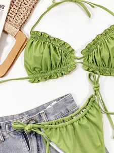Flat lay of bright green ruffled bikini set with neck halter and side-tie bottoms