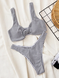 Detailed flat lay of black and white gingham bikini set with knot front top and high cut bottoms