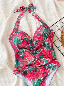 Detail of tropical leaf print one-piece swimsuit with halter neck and ruched belly