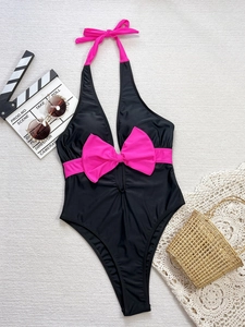 Flat lay detail of a one-piece black swimsuit featuring a vibrant pink bow and neck ties