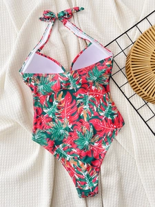 Detail of floral one-piece swimsuit with halter neck bow and tropical leaf print pattern
