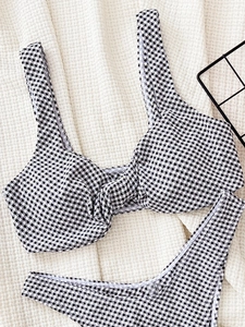 Flat lay of black and white gingham bikini set with knot detail on waffle fabric