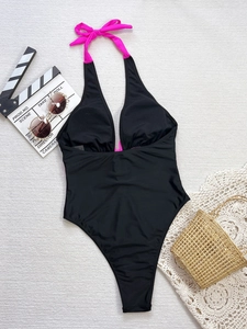 Detail of black one-piece swimsuit with pink halter bow and high-cut V-neck design