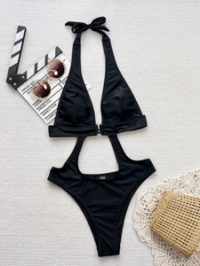 Sexy black one-piece swimsuit with halter neck and cutout design on beach accessories