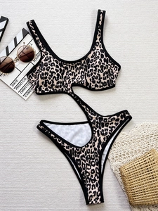 Leopard print cutout monokini swimsuit with beach accessories on white textured background