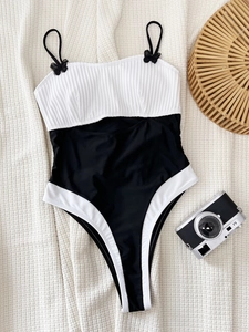 One-piece swimsuit with black and white color blocking and bow details on straps