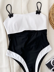 Chic black and white one-piece swimsuit with ribbed texture and decorative shoulder bows