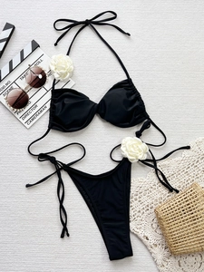 Detailed view of black two-piece bikini with white 3D rose flowers on shoulder and hip