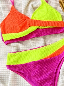 Detailed flat lay of textured seersucker bikini with neon orange and pink color blocking