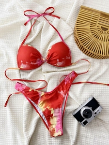 Flat lay of red and pink tie-dye bikini with neck tie and high-cut bottoms